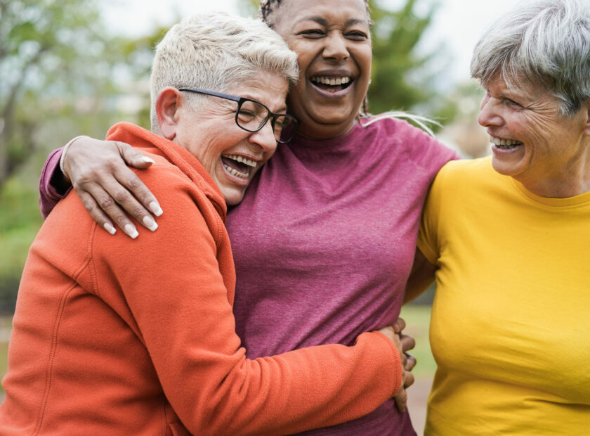 Multiracial senior women having fun together hugging each others - Main focus on right female face