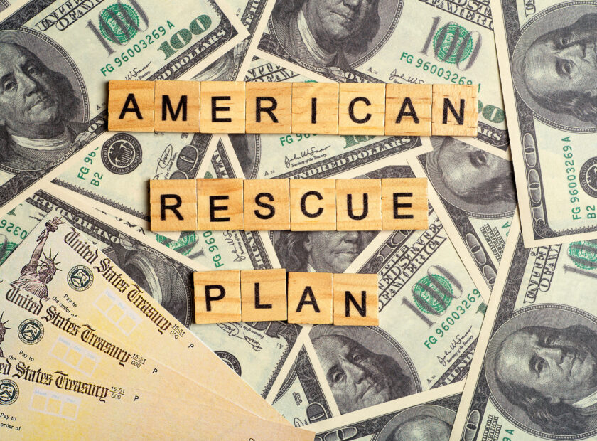 wood tiles spelling out "American Rescue Plan" over layer of cash