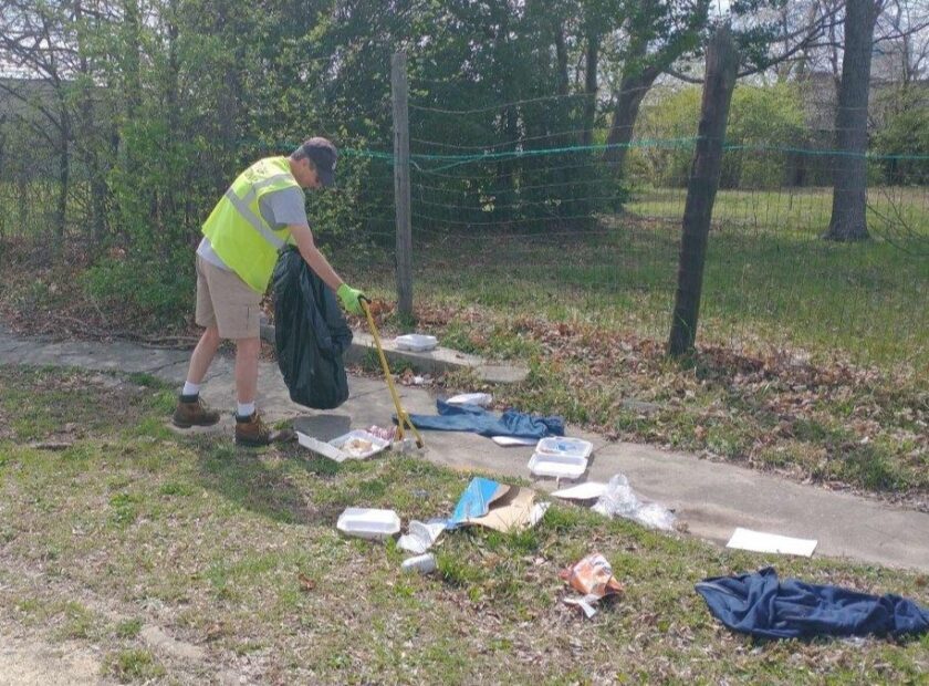 Man in reflective vest collecting roadside litter