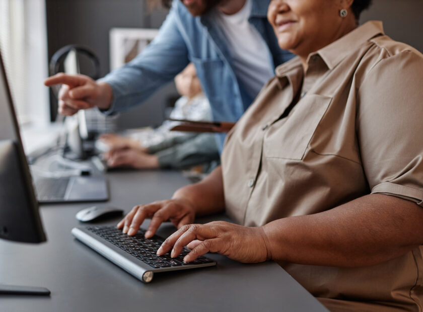 Closeup of black senior woman using computer with teacher in computer class