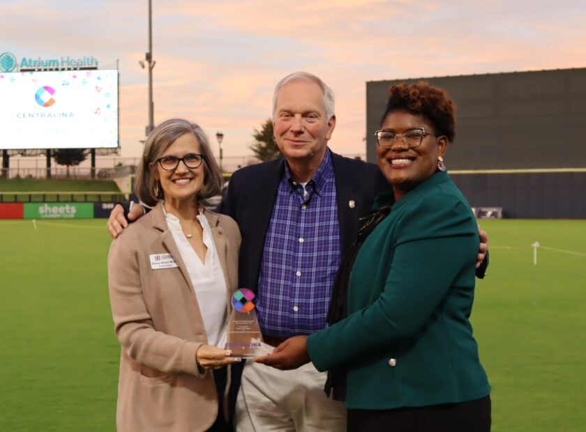 three people standing together and holding an award